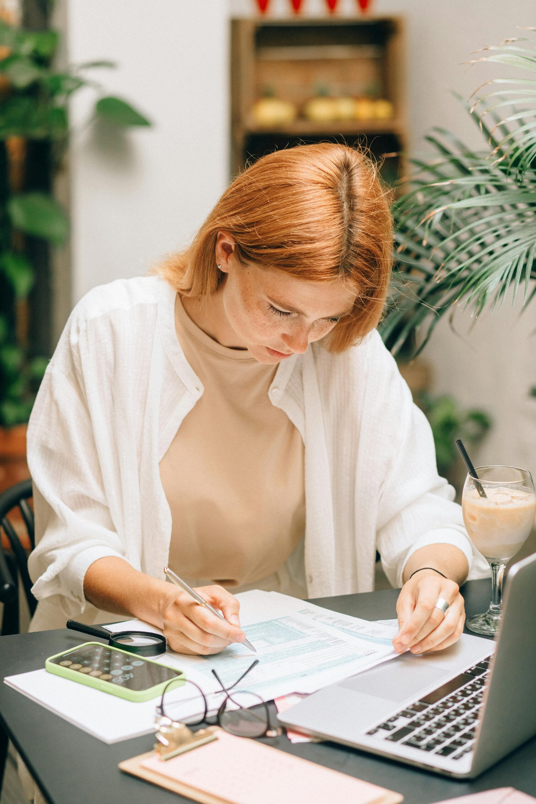 pexels-photo-8927463-8927463 Woman analyzing financial documents using laptop and calculator indoors.